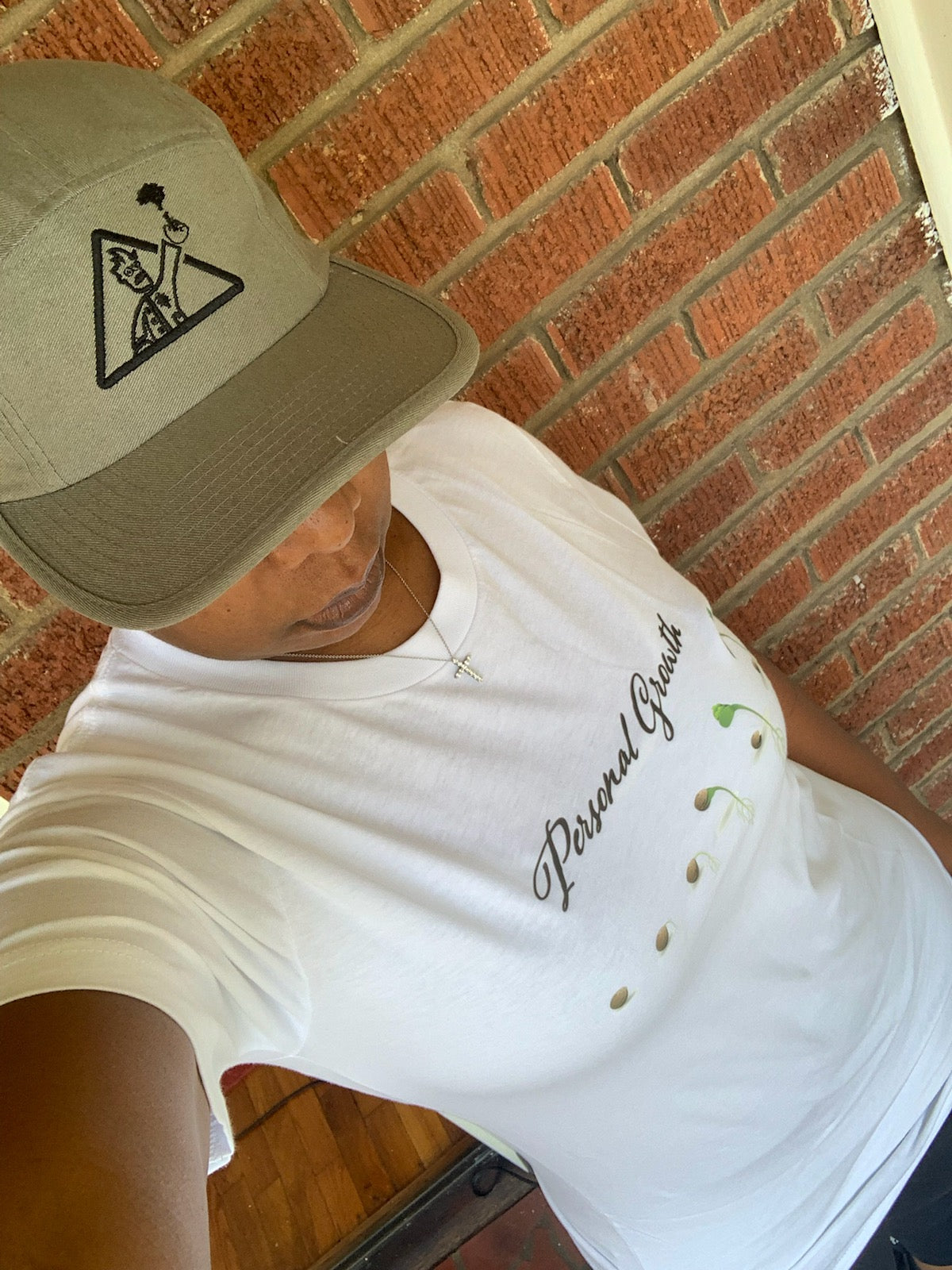 Person wearing a white t-shirt with 'Personal Growth' lettering and a cap, showcasing the personal growth collection.